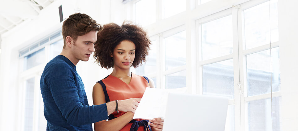 A man and woman sharing a moment, both looking intently at a laptop, possibly reviewing information or working together.