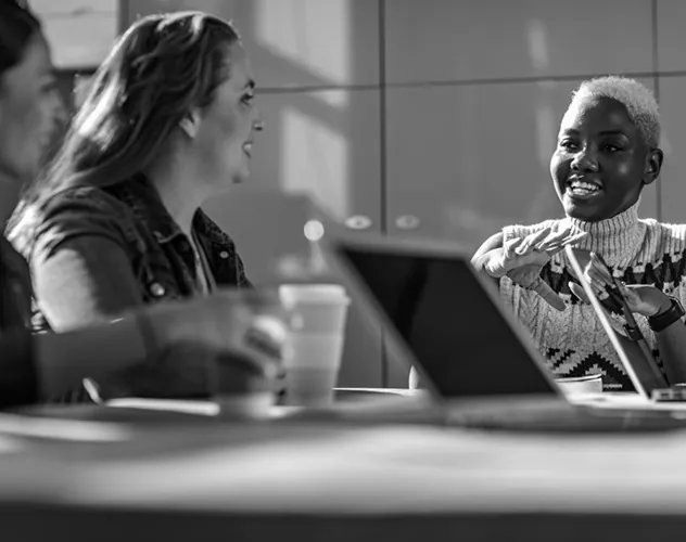 Three women working on laptops at a table.