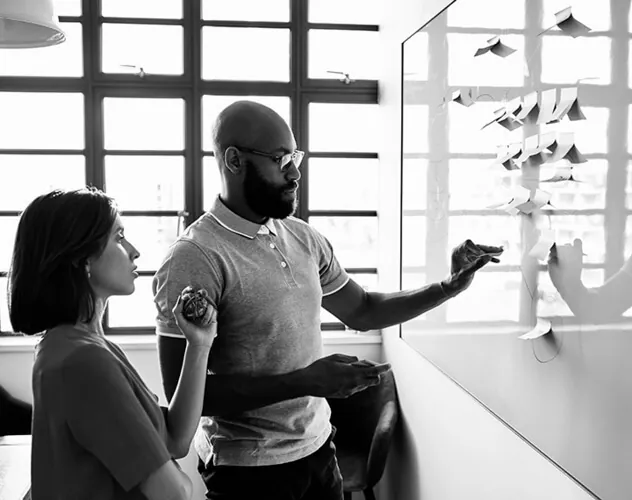 Young woman and male colleague writing ideas on adhesive notes